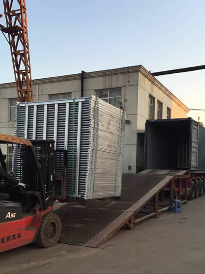 A worker is loading the horse corral panels into container.
